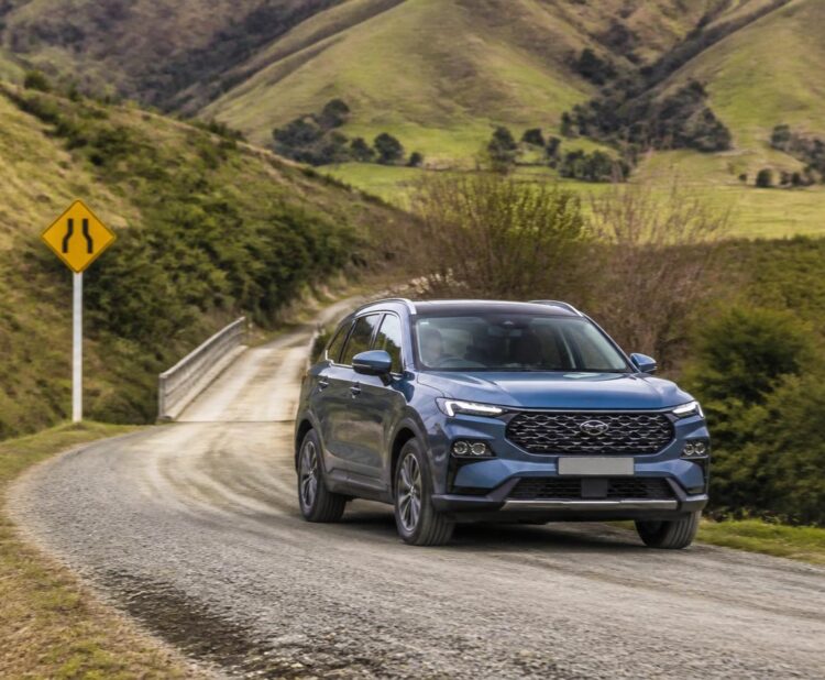 Family SUV driving safely on a winding rural road in New Zealand